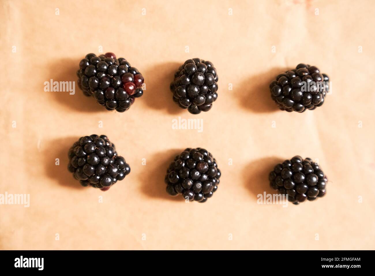 Six blackberries on a beige craft paper background. Berries laid out in the form of a rectangle. Horizontal card. Healthy, delicious, natural vegetarian background. Stock Photo