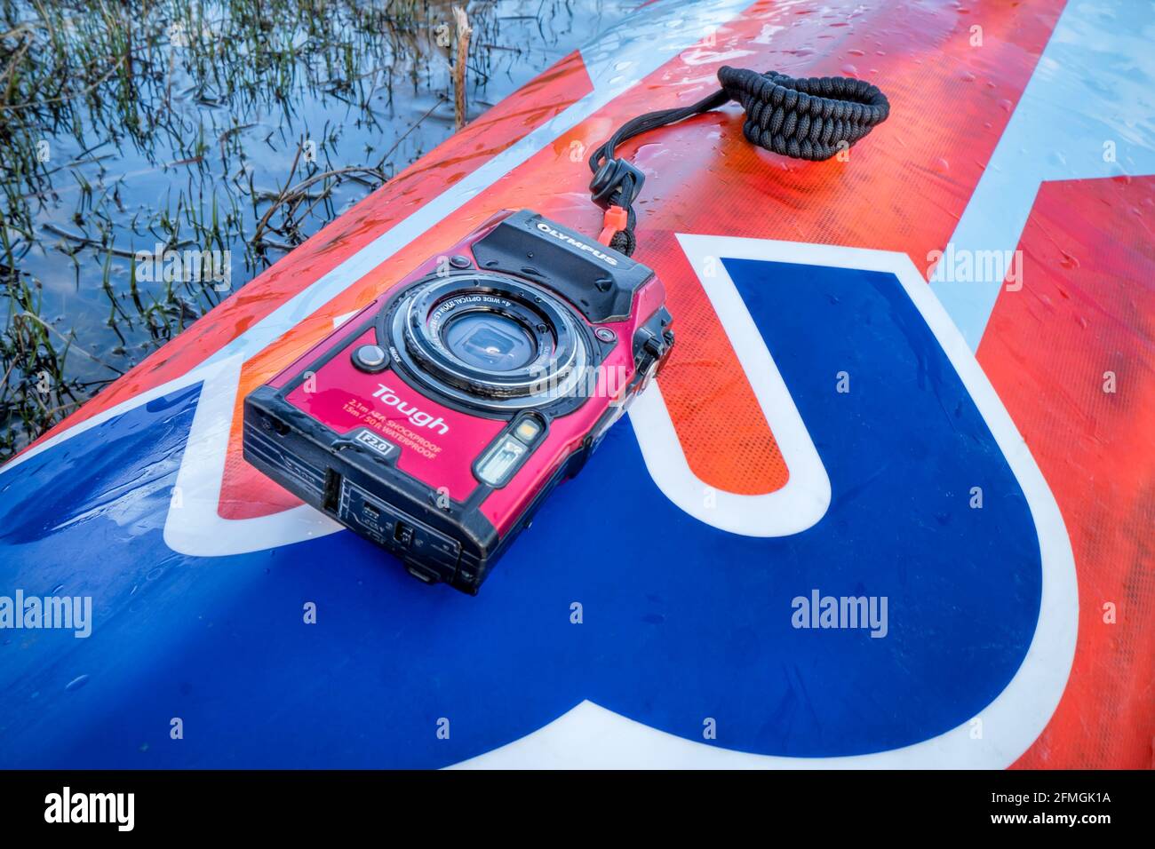 Fort Collins, CO, USA - May 4, 2021: Compact, waterproof Olympus Stylus Tough TG-5 camera on a wet deck of a stand up paddleboard by Mistral Stock Photo