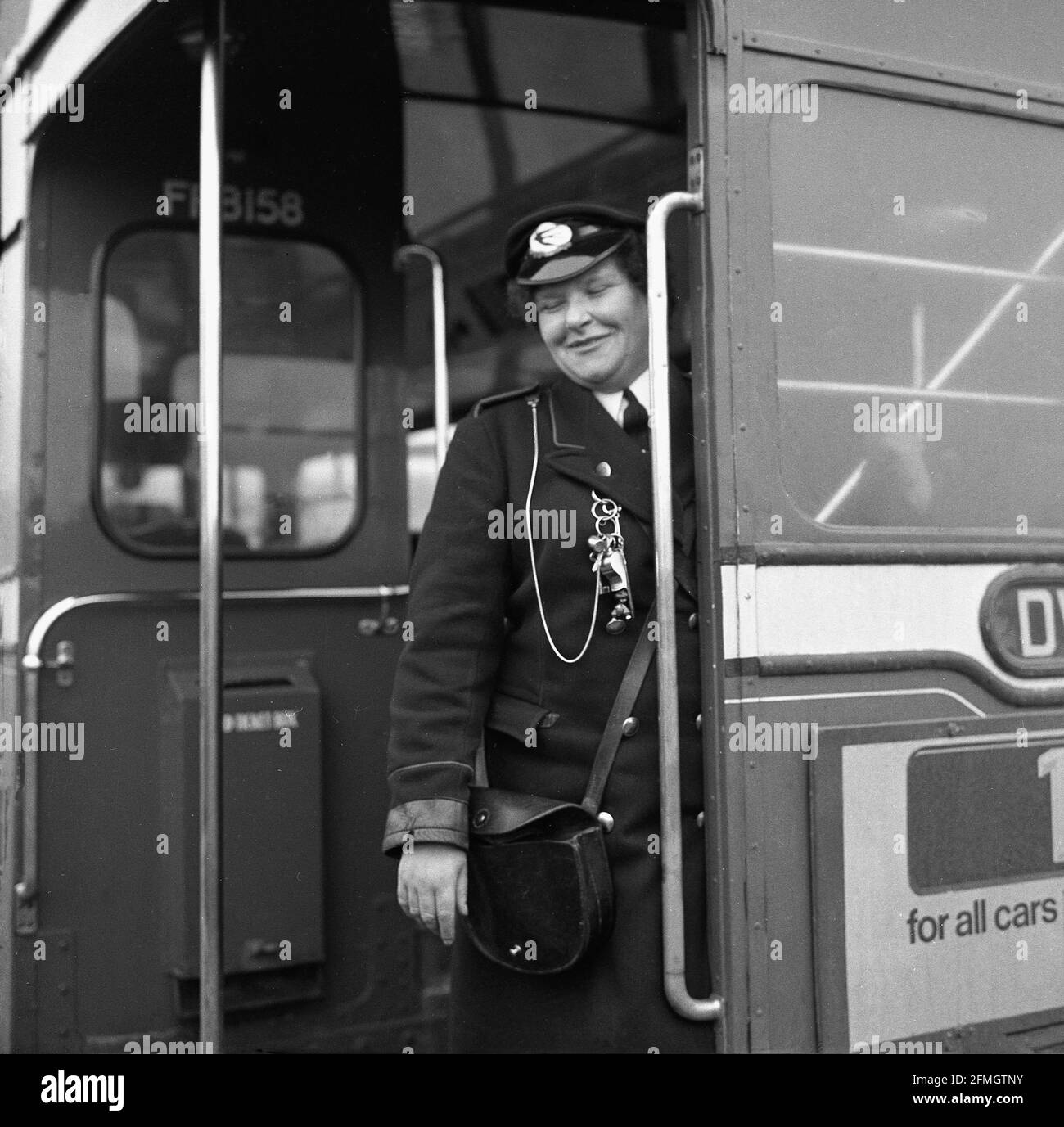 1960s, historical, a lady bus conductor standing at the back entrance, by the staircase, of a routemaster double-decker bus, Scotland, UK. These ladies were known as 'clippies' during WW2 due to their ticket machines which 'clipped' the tickets. Conductors, both female and male, were an essential part of the operation of a double decker bus being at the opposite end to the driver who was in a sealed cabin. Stock Photo