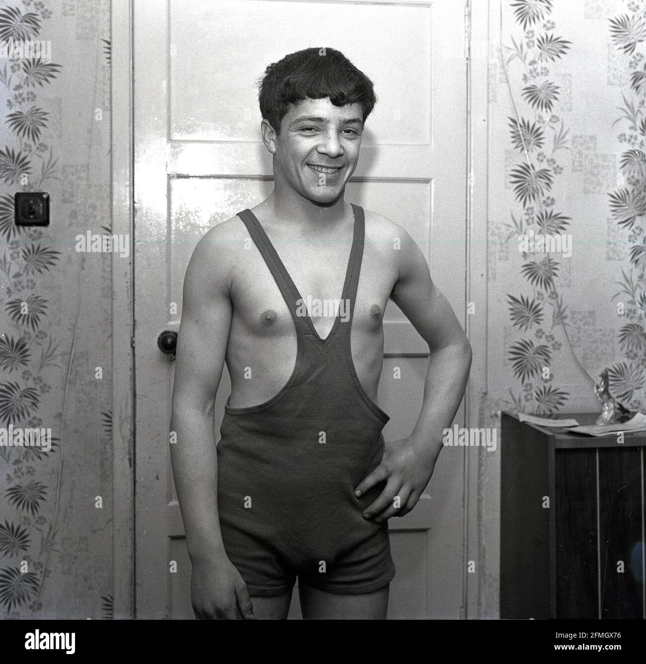 1960s, historical, a young male wrestler standing in his wrestling singlet or simply singlet, Kelty, Scotland, UK. The singlet is a one-piece, tight fitting costume or sports kit, which covered the body from the middle of the chest but left the top half of the body and arms free without covering, Although the one-piece singlet is well-known as the traditional uniform of the sport, infact it has only been widely in use from the late '50s, with wrestlers before then, wearing pants over leggings with or without a vest, when competing. Wrestling was a popular activity in the Highland Games. Stock Photo