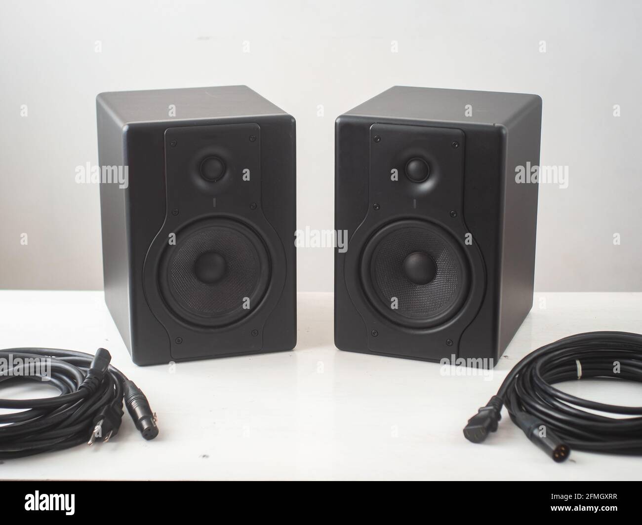 Black Pro Studio Speakers with Cables against a White and Gray Surface