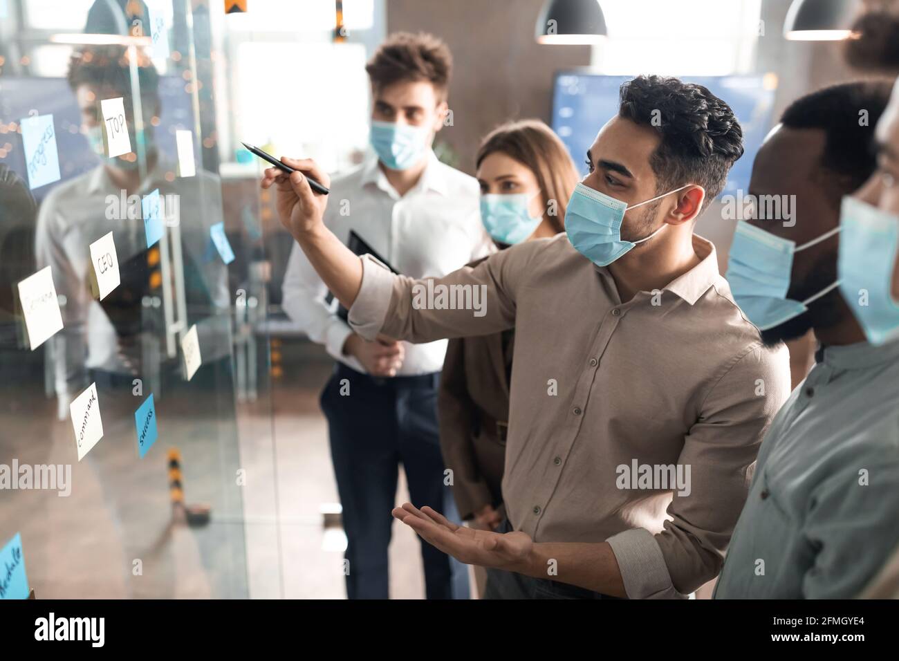 Businesspeople having meeting using sticky post-it notes on glass wall Stock Photo