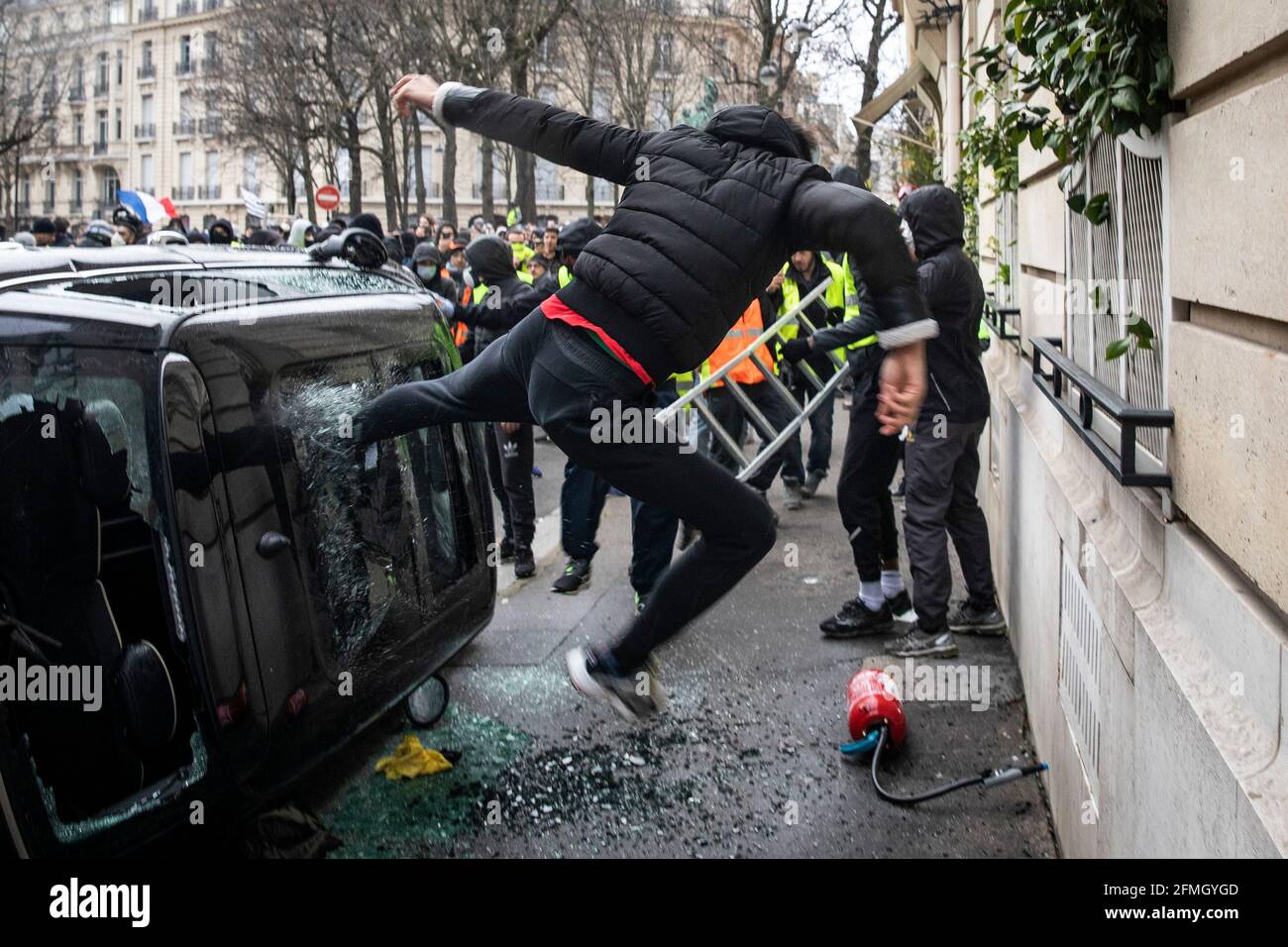 A protester smashes the roof window of a vehicle on a road near the Arc de Triomphe during the fourth Saturday of national protests by the 'yellow ves Stock Photo
