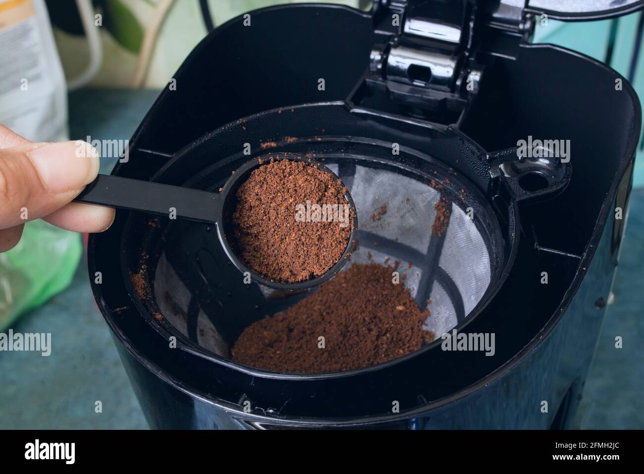Spoon pours coffee into the container of the coffee maker close up Stock Photo