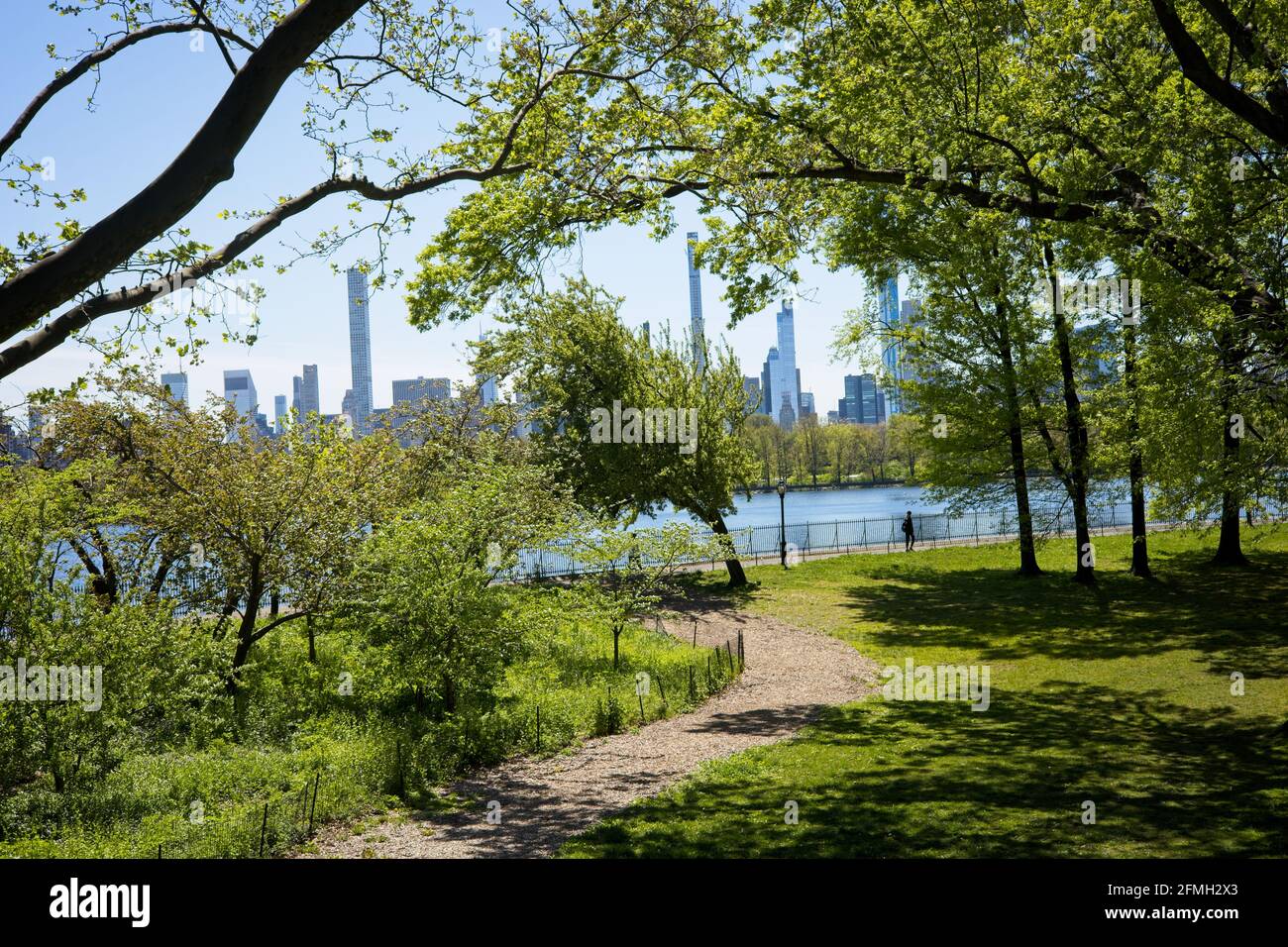 New York, NY, USA - May 9, 2021: Pathway in Central Park leading to Onassis Reservoir with supertall skyscrapers in background Stock Photo