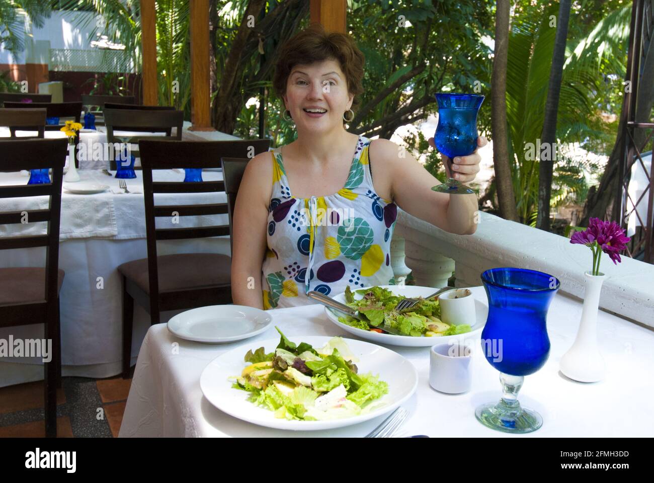 Woman toasting in riverside restaurant on Cuale River Island, vibrant market place, Puerto Vallarta, Mexico.#PV613 Stock Photo