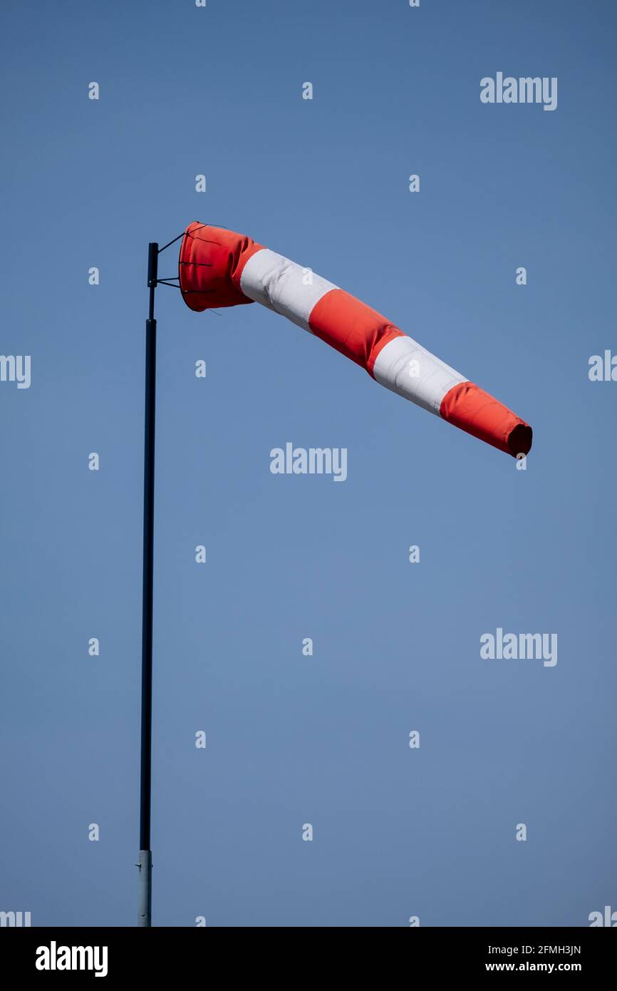Helsinki / Finland - MAY 9, 2021: Closeup of striped windsock waiving in the wind against a bright blue sky. Stock Photo