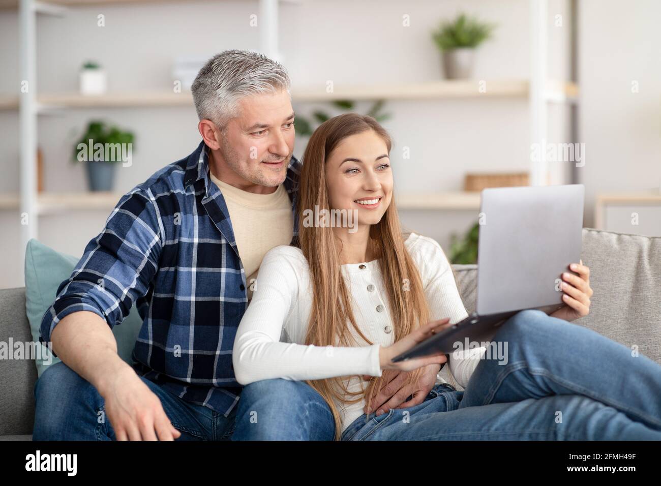 Happy mature couple using laptop, relaxing together at home Stock Photo