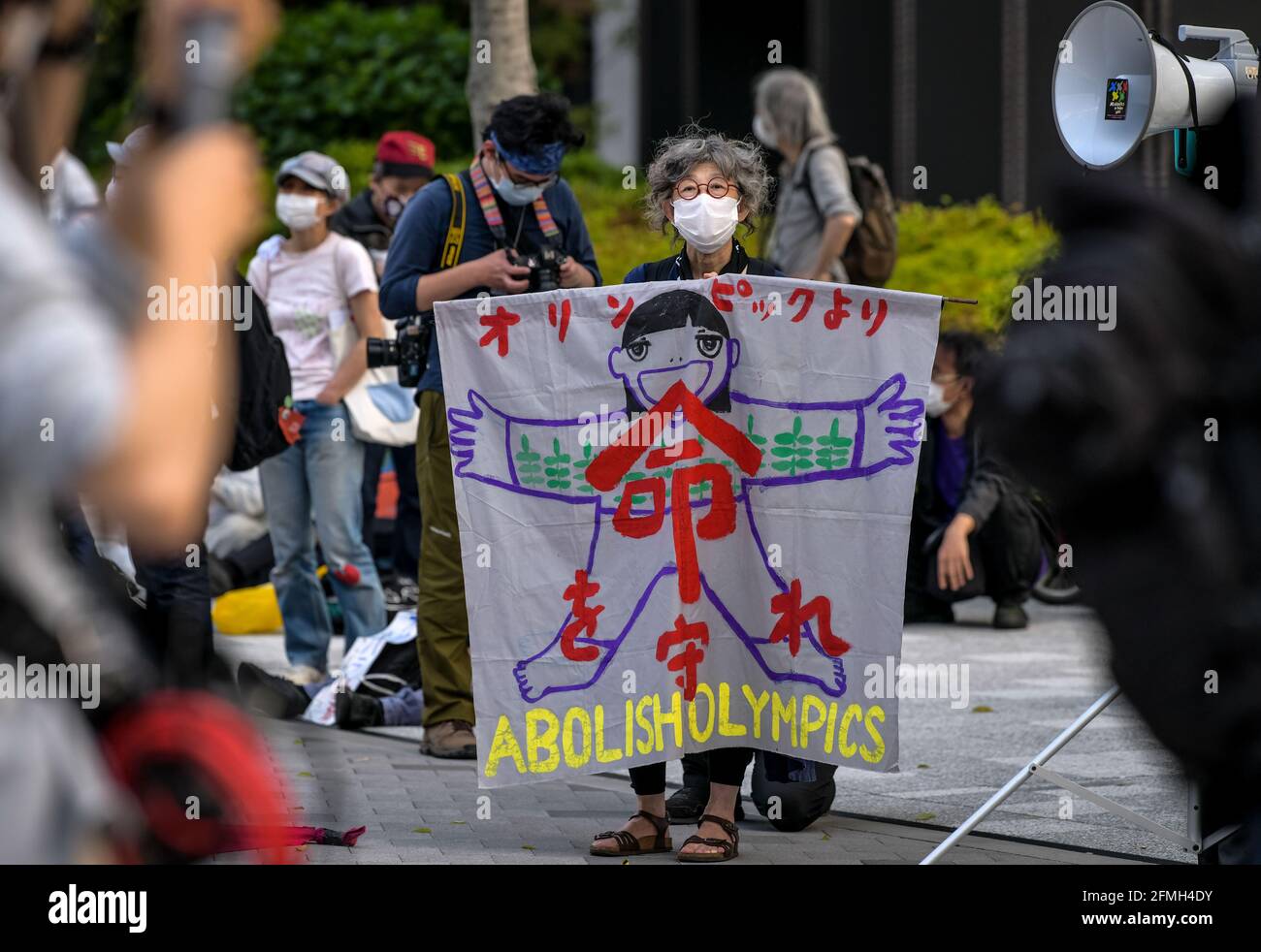 Tokyo, Japan. 09th May, 2021. A protester holds a banner during a protest against the Tokyo Olympics in front of the New National Stadium, the main stadium for the Tokyo Olympics. With less than 3 months remaining until the opening of the Tokyo 2020 Olympics concern continues to linger in Japan over the feasibility of hosting such a huge event during the ongoing COVID-19 pandemic. (Photo by Cezary Kowalski/SOPA Images/Sipa USA) Credit: Sipa USA/Alamy Live News Stock Photo