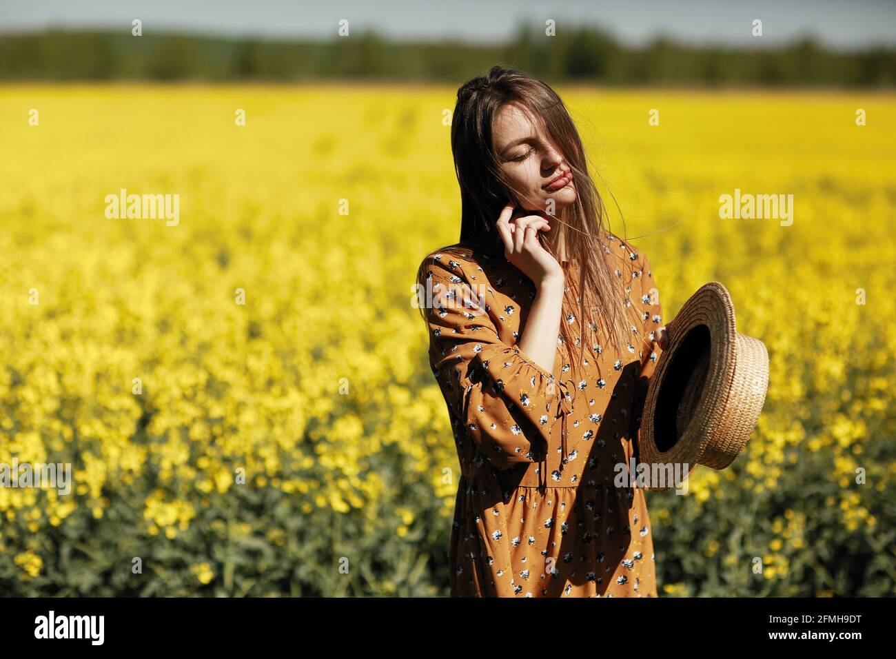beautiful young woman walks in a field of yellow rapeseed. Girl ...