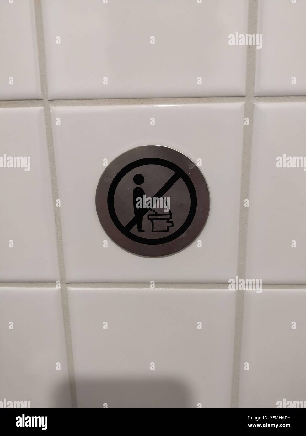 A "Do not pee while standing" sign on the tiled wall Stock Photo Alamy