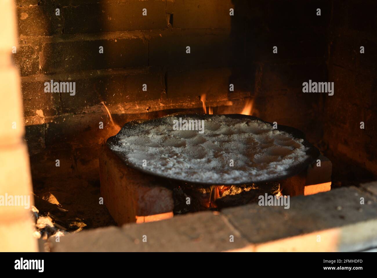 Frying pan with salt in fireplace. Cleaning a frying pan over a fire by