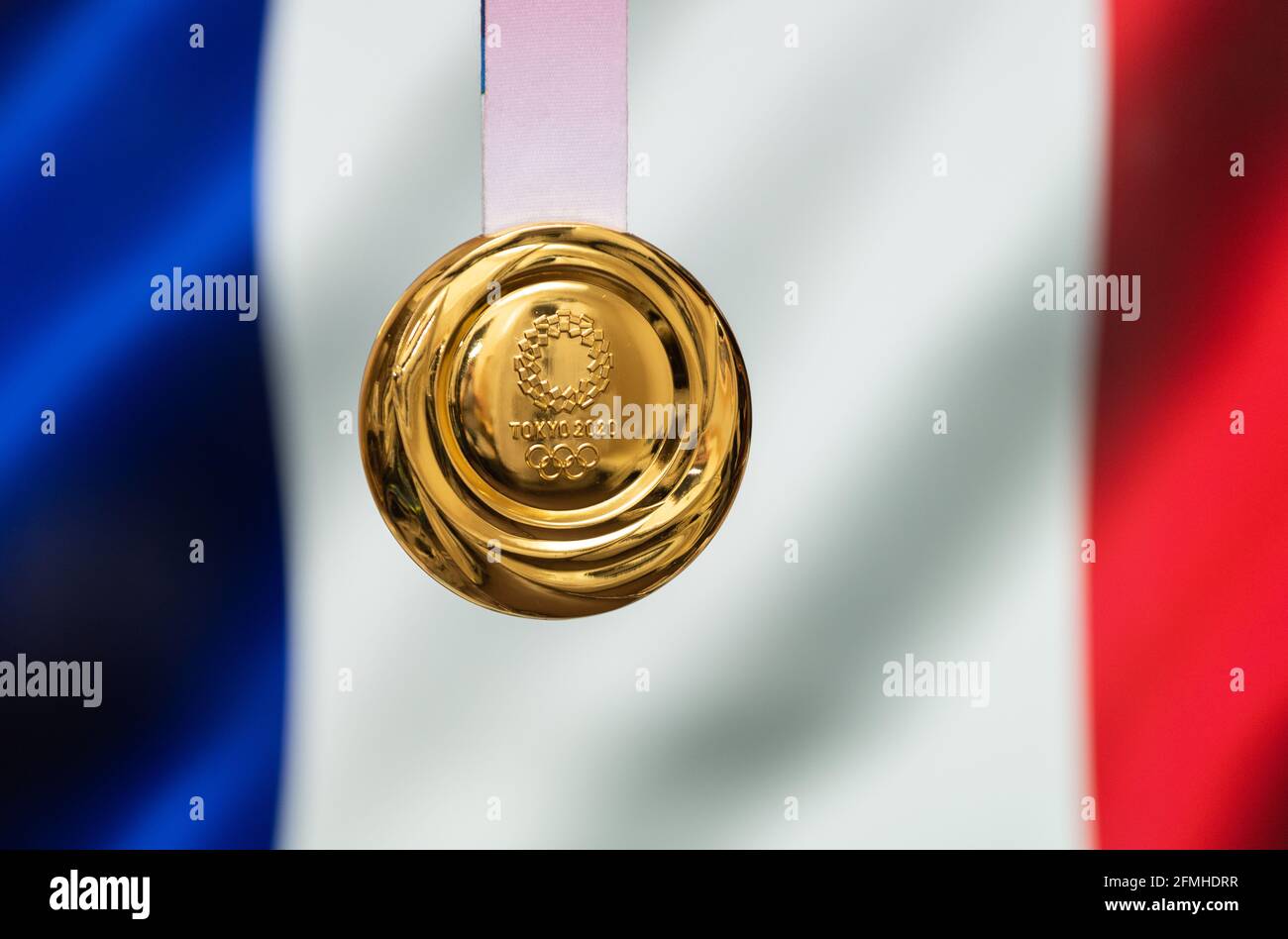 April 25, 2021 Tokyo, Japan. Gold medal of the XXXII Summer Olympic Games 2020 in Tokyo on the background of the flag of France. Stock Photo