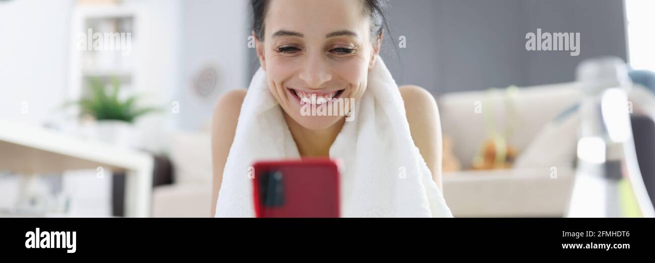 Woman in sportswear lying on gymnastic mat and looking on phone screen Stock Photo