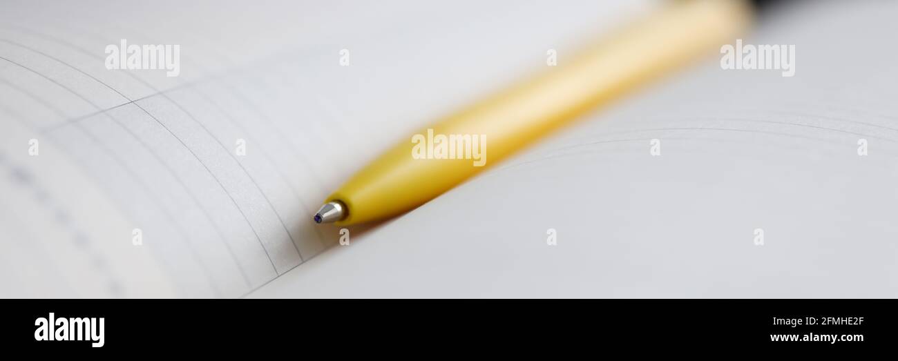 Yellow ballpoint pen lying on notebook closeup Stock Photo