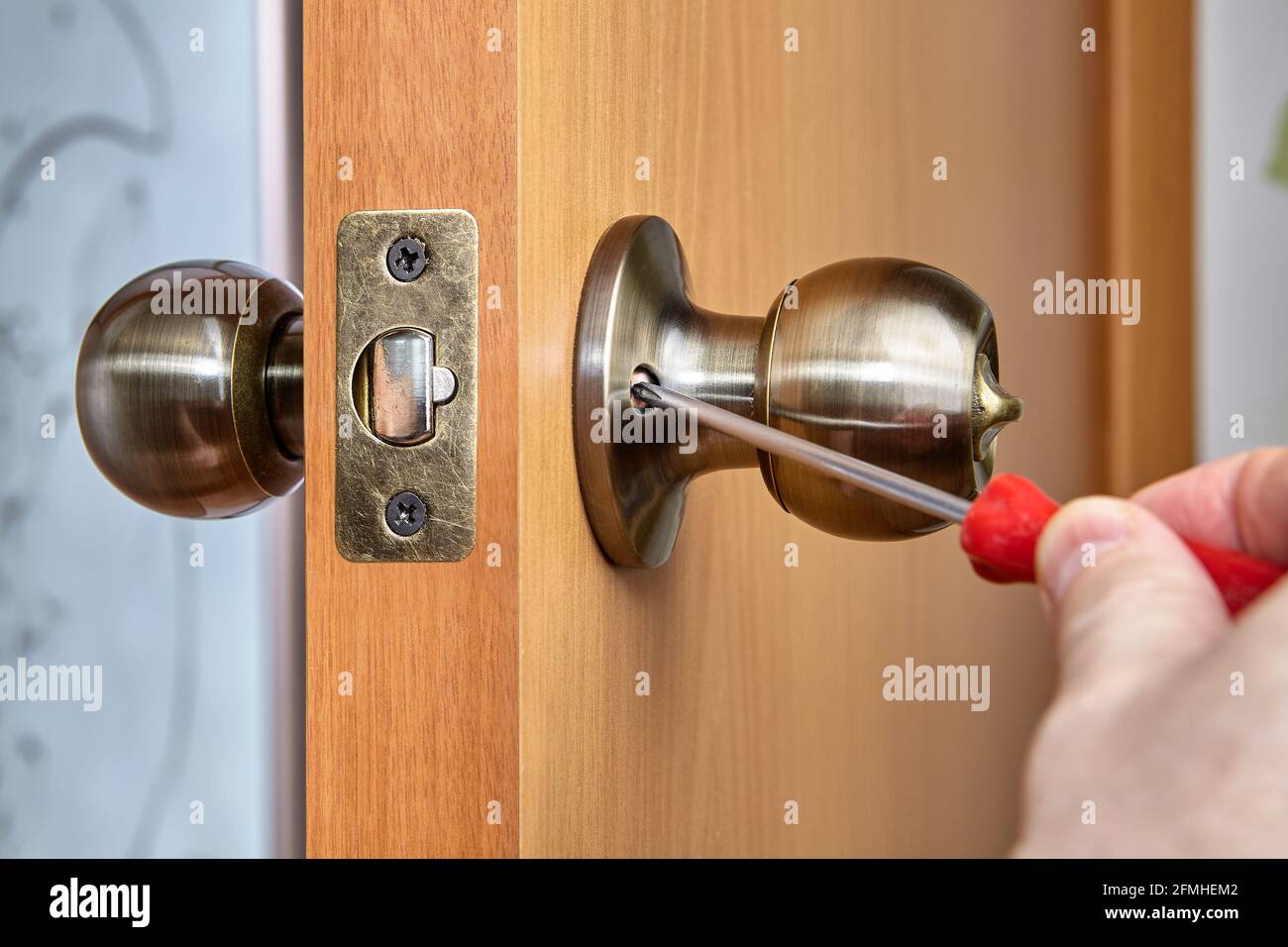 Joiner uses screwdriver to secure both handle sides to door. Stock Photo