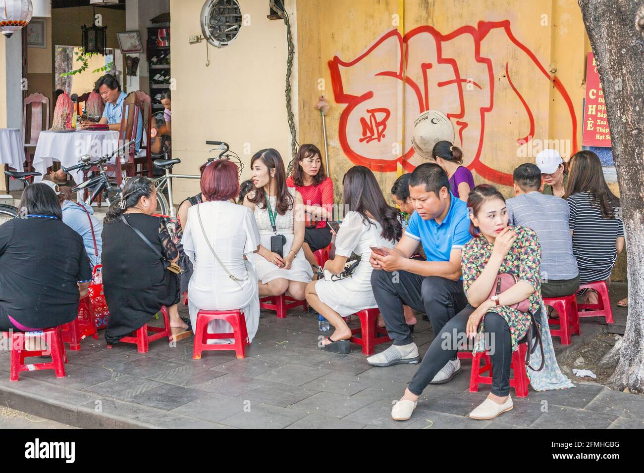 Vietnamese families sitting on red stools at street food cafe, Hoi An, Vietnam Stock Photo Alamy
