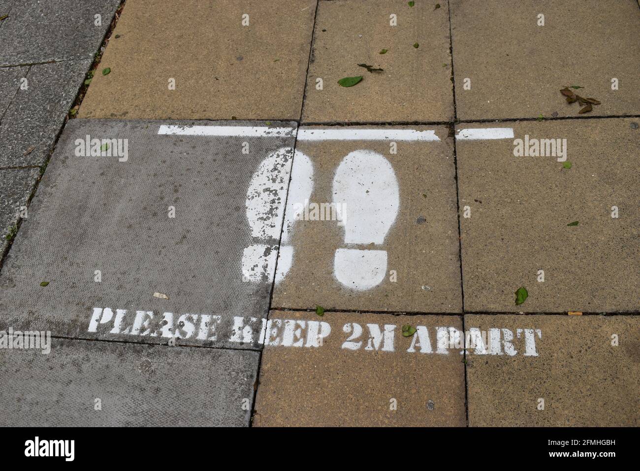 Social distancing notice on pavement: Please keep 2m apart. Stock Photo