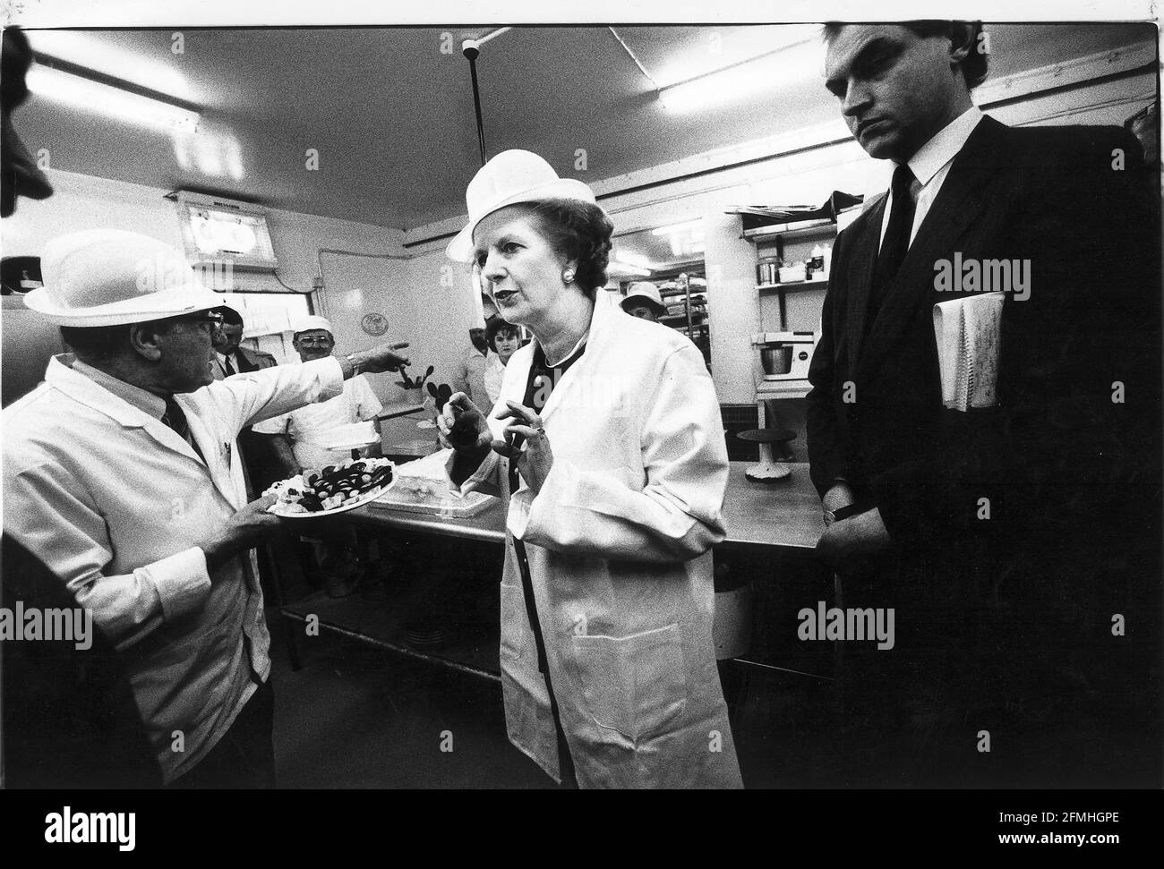 Margaret Thatcher visits cake producer in Liverpool wearing white coat and hat Stock Photo