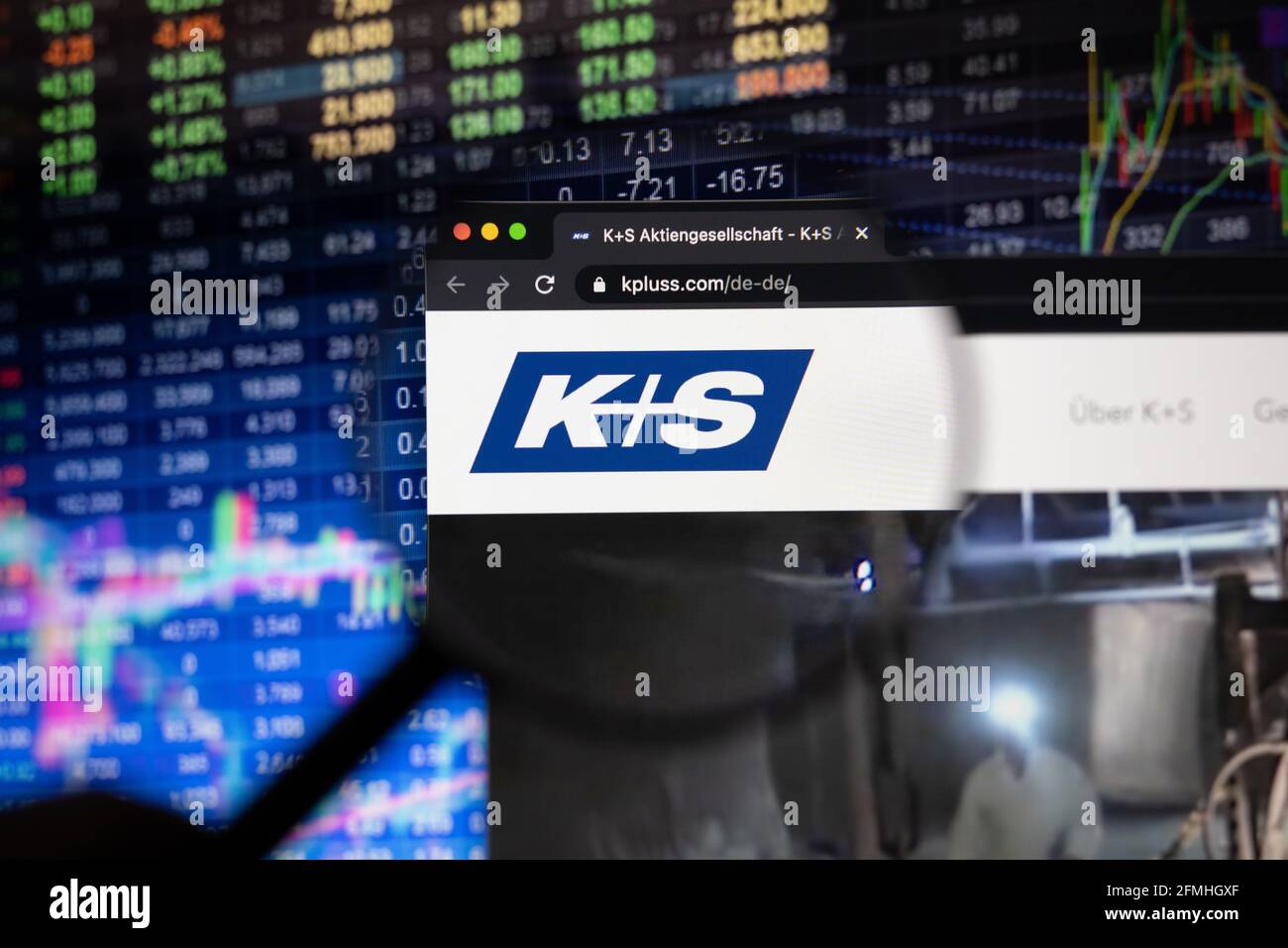 K+S company logo on a website with blurry stock market developments in the background, seen on a computer screen through a magnifying glass Stock Photo