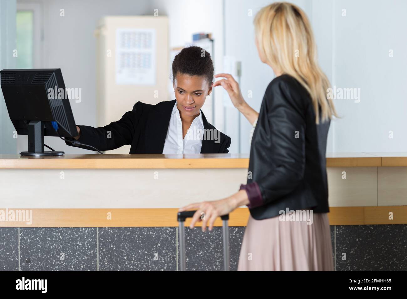 receptionist at hotel reception handing over a key to guest Stock Photo