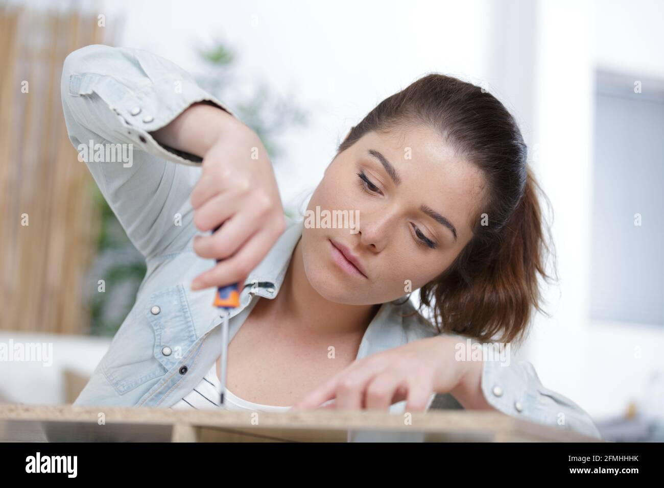 a young woman using screwdriver Stock Photo