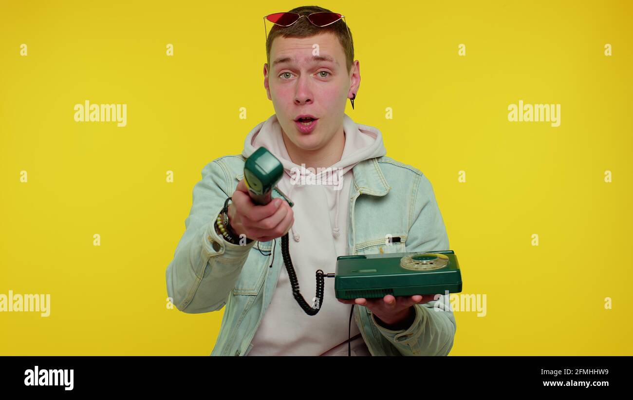 Cheerful teen man secretary talking on wired vintage telephone of 80s