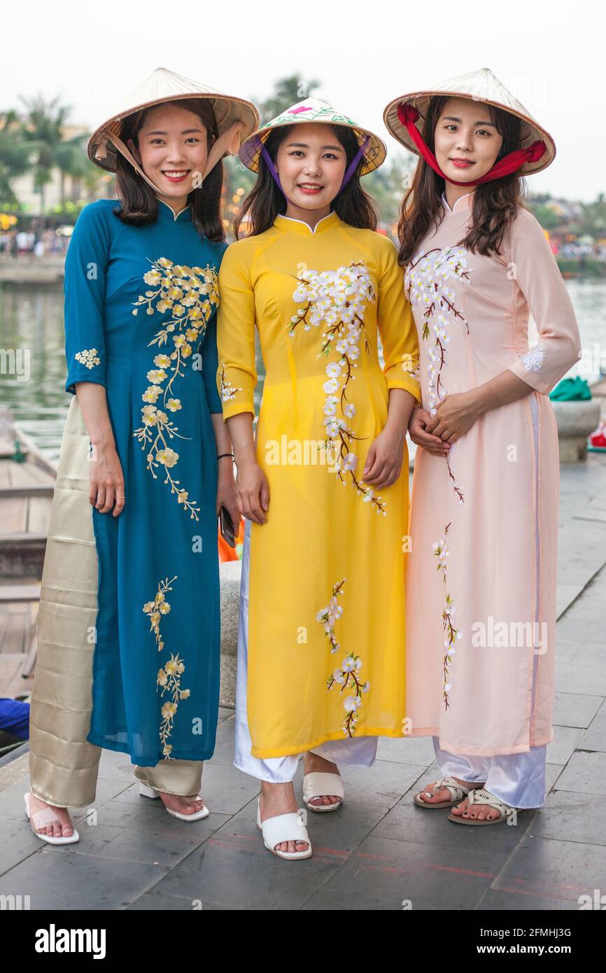 https://c8.alamy.com/comp/2FMHJ3G/three-pretty-vietnamese-women-wearing-conical-hats-and-traditional-ao-dai-dresses-pose-for-camera-by-old-town-riverside-hoi-an-vietnam-2FMHJ3G.jpg