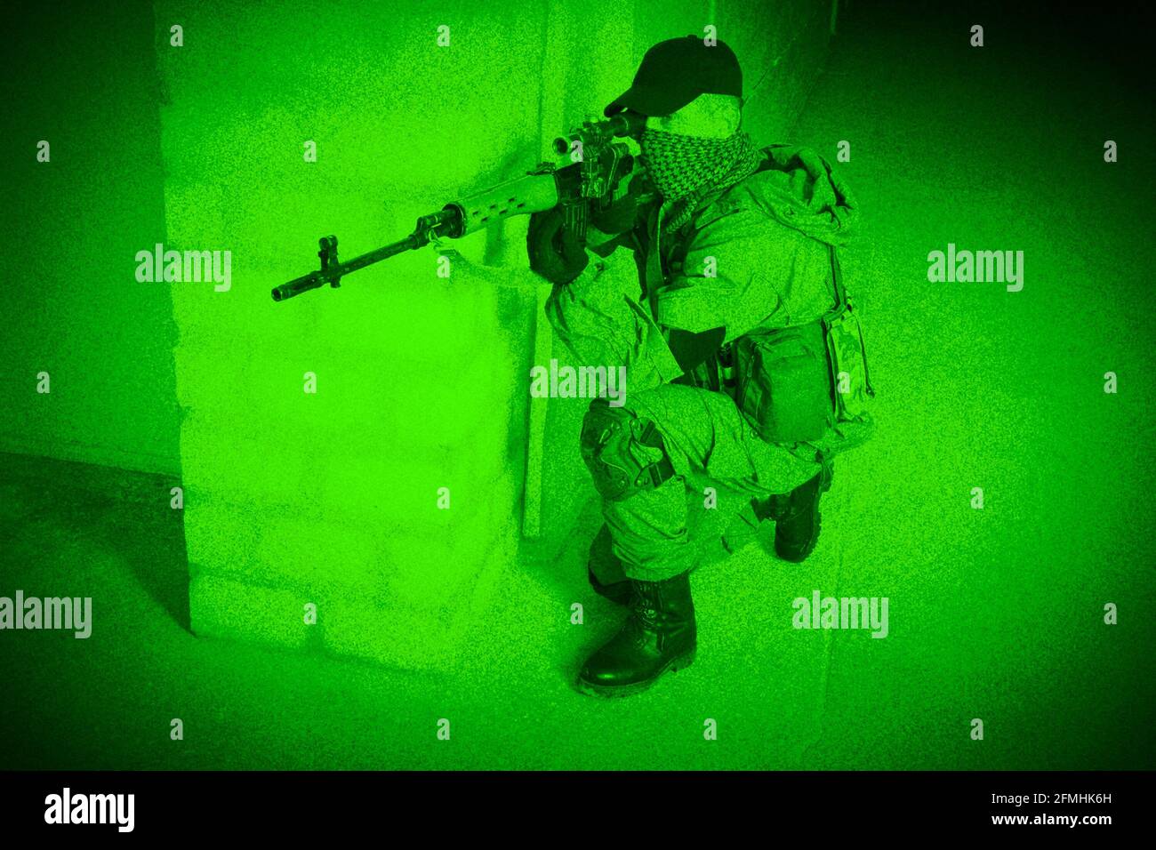 Mercenary sniper firing sniper rifle inside the building. View through night vision. Stock Photo
