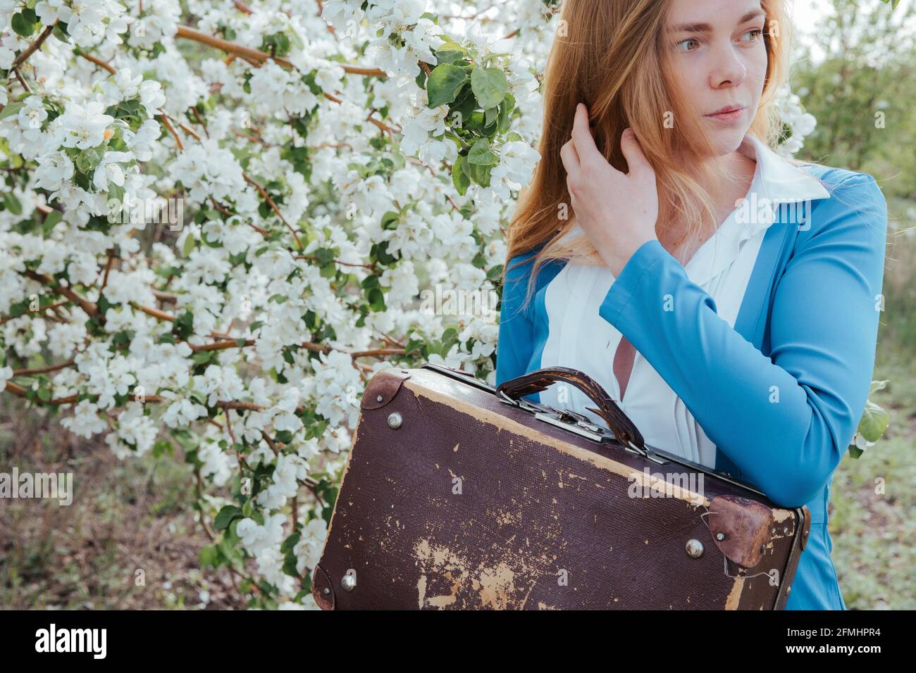 A young woman holds an old suitcase in her hands.  Stock Photo