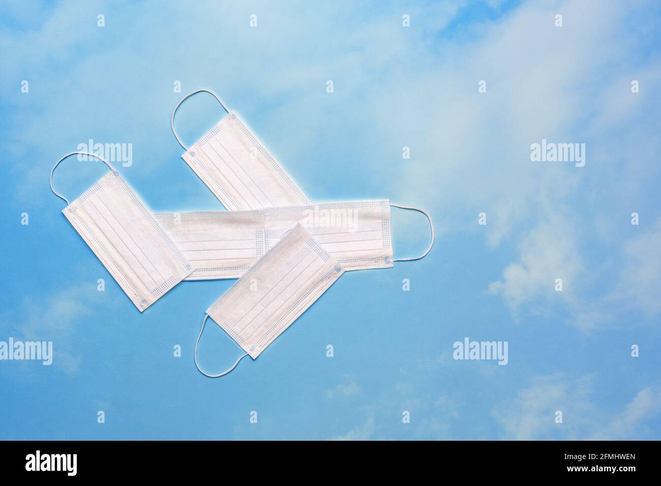 Airplane model made of protective masks on a bright blue sky with