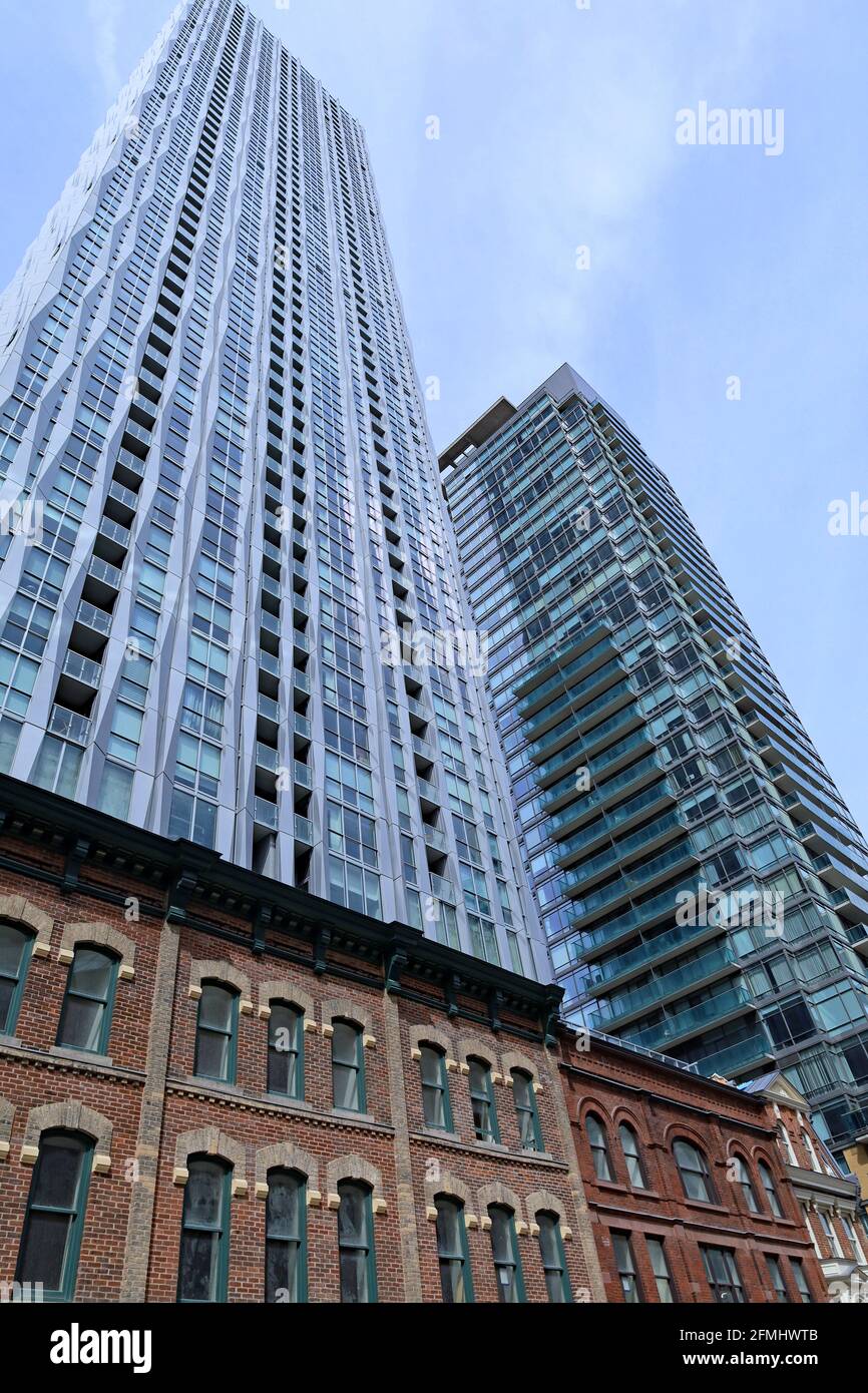 Toronto, Canada - May 9, 2021:  A modern high rise apartment building  just built, with 19th century facades preserved at its base. Stock Photo