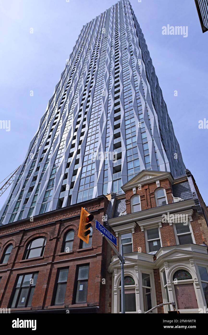 Toronto, Canada - May 9, 2021:  A modern high rise apartment building  just built, with 19th century facades preserved at its base. Stock Photo