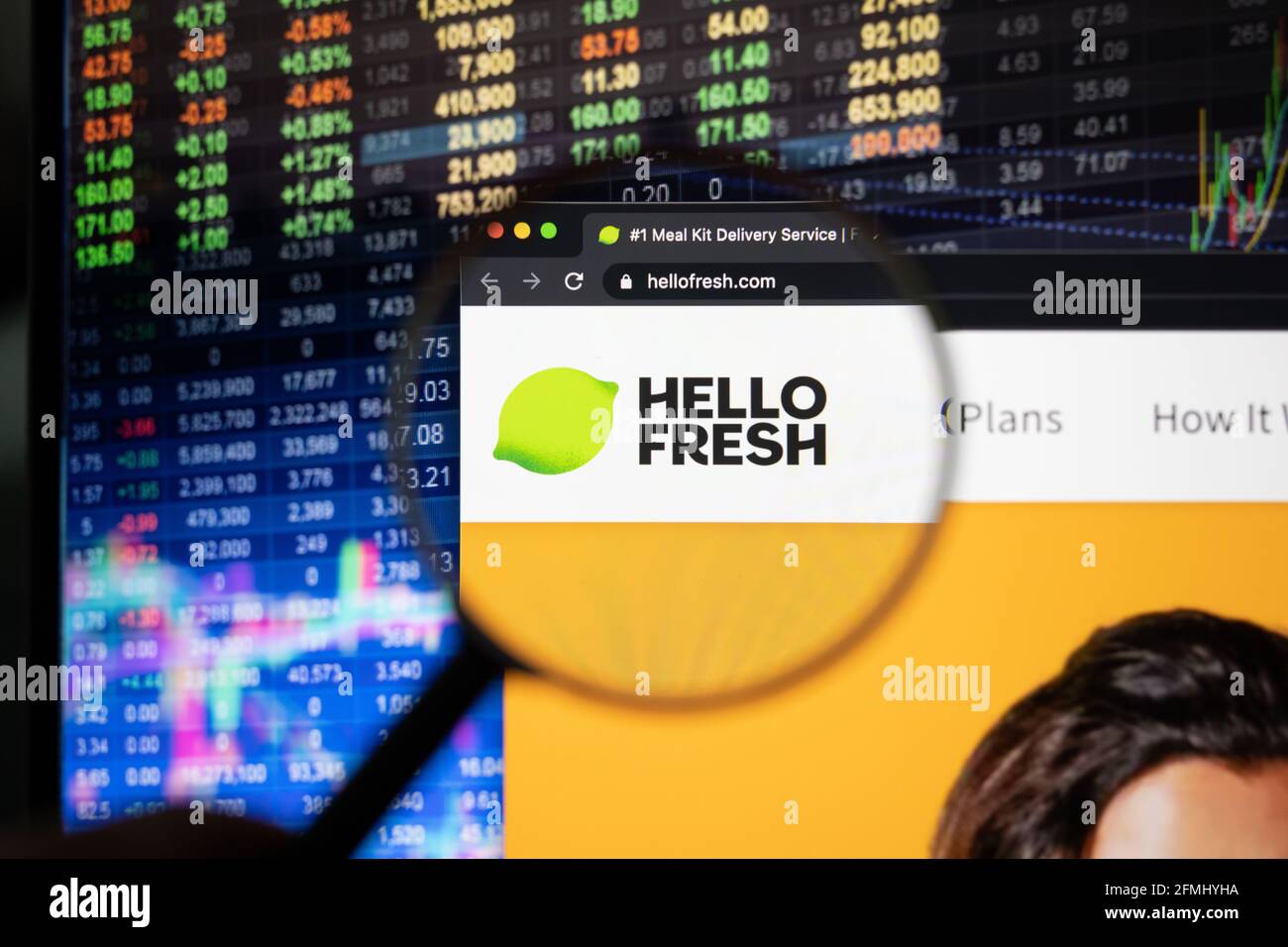 Hellofresh company logo on a website with blurry stock market developments in the background, seen on a computer screen through a magnifying glass Stock Photo