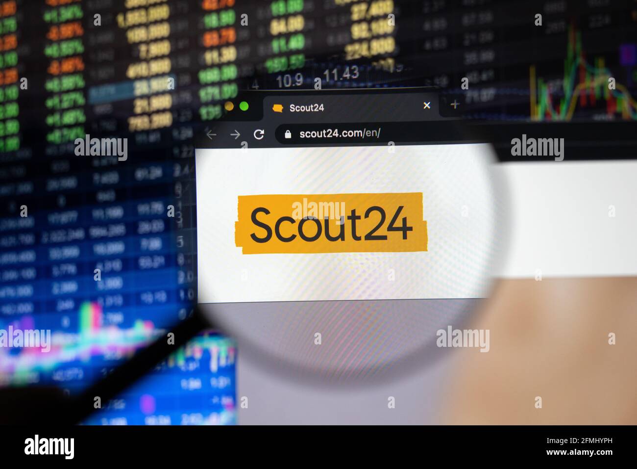Scout24 company logo on a website with blurry stock market developments in the background, seen on a computer screen through a magnifying glass Stock Photo