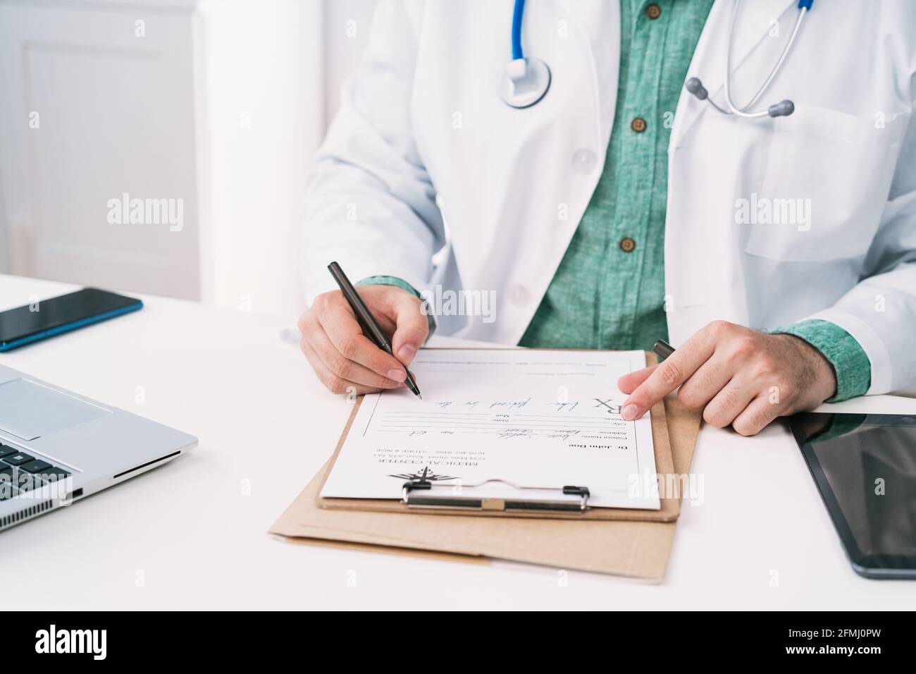 Cropped unrecognizable uniform with stethoscope taking notes on paper sheet while working in clinic Stock Photo