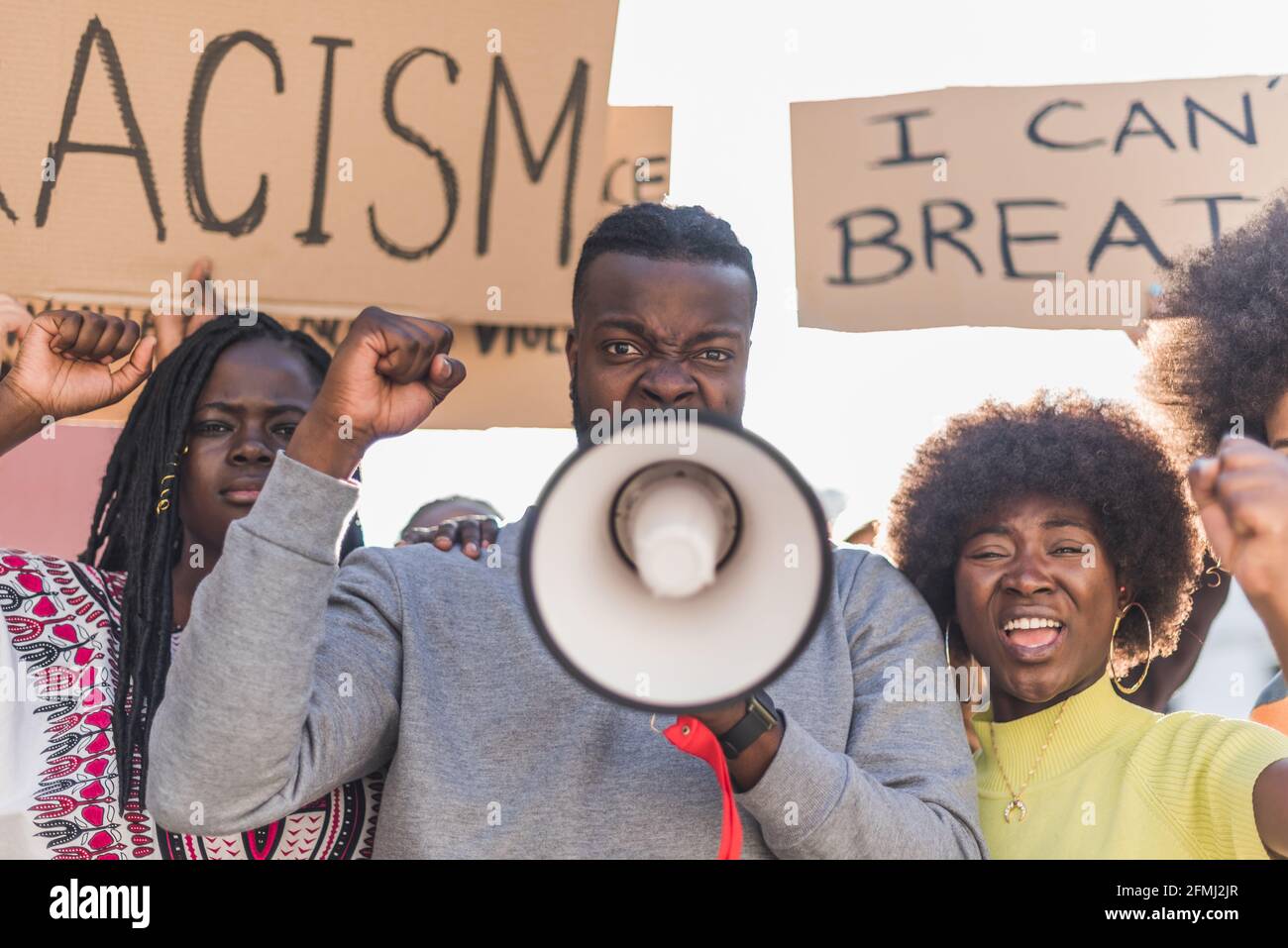 African American male screaming in megaphone looking at camera during Black Lives Matter protest in city while standing in crowd of multiethnic demons Stock Photo