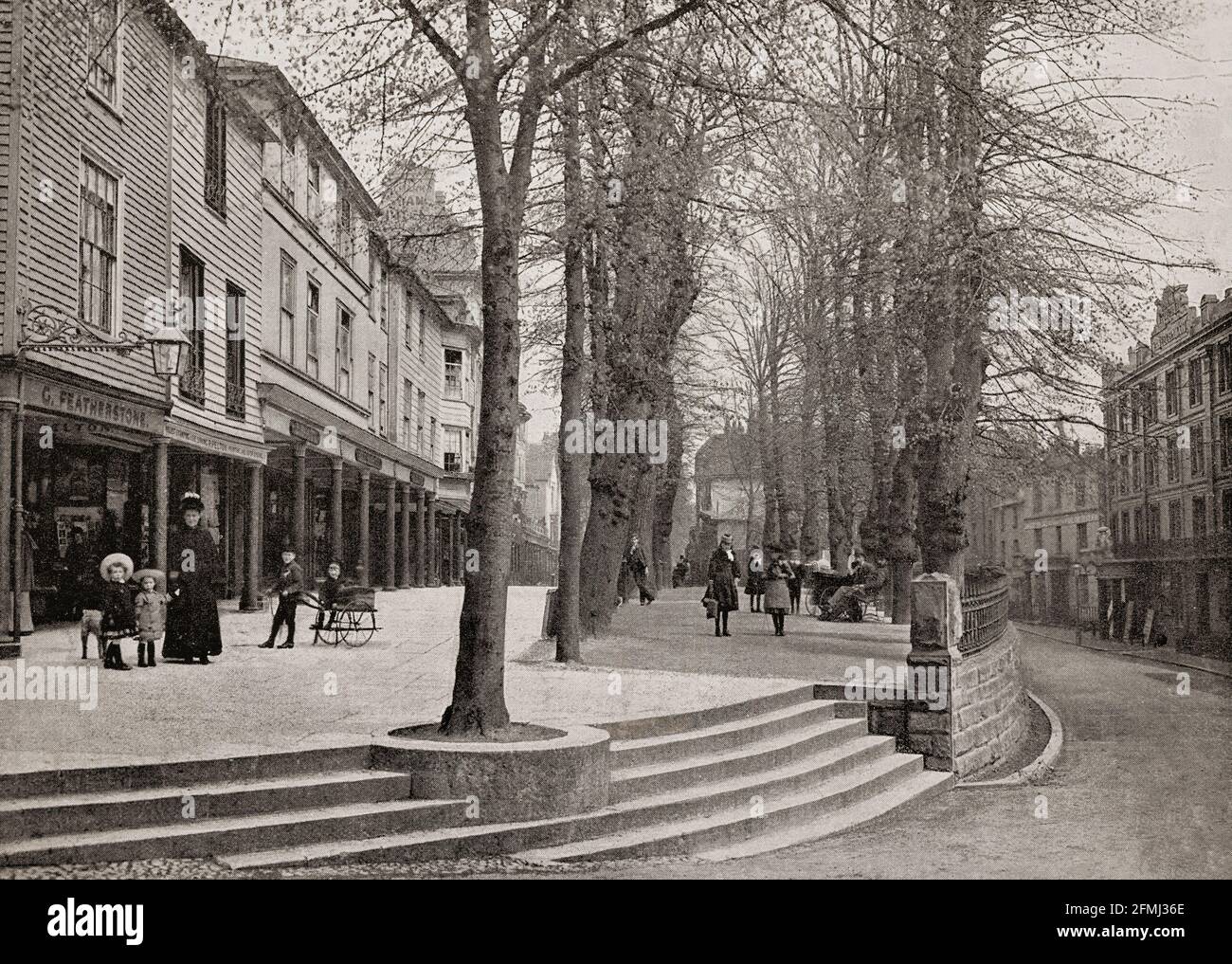 A late 19th Century view of The Pantiles, a Georgian colonnade in the town of Royal Tunbridge Wells, Kent, England constructed in the first part of the 18th century. Formerly known as The Walks and the (Royal) Parade, it leads from the well that gave the town its name. The pantiles used to pave the Upper Walks should not be confused with roofing pantiles. The paving installed there comprised one-inch thick square tiles made from heavy wealden clay, so named because they were shaped in a wooden pan before firing. Stock Photo
