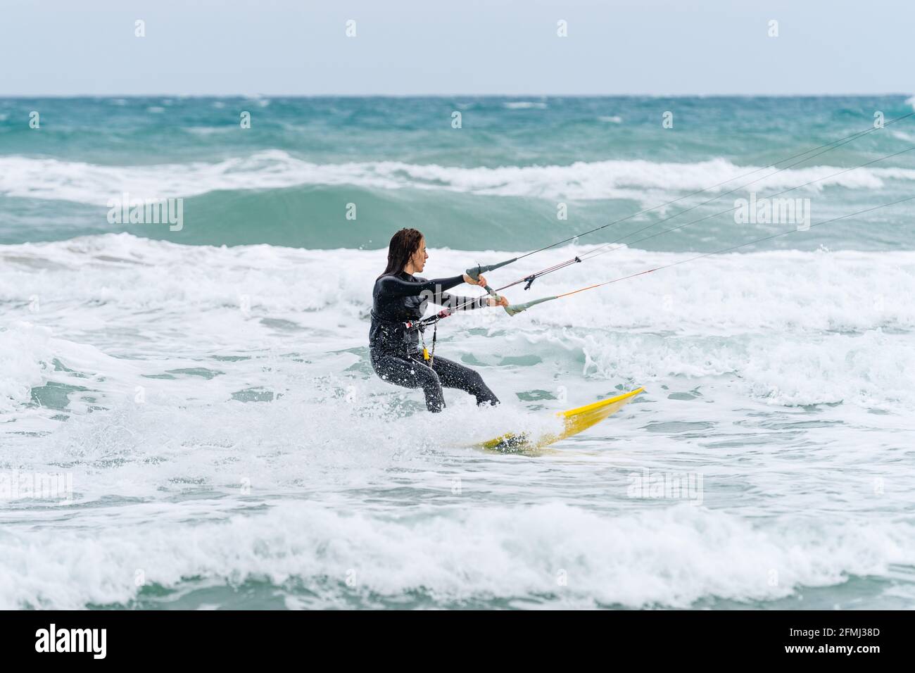 Active female athlete on kiteboard holding control bar while practicing