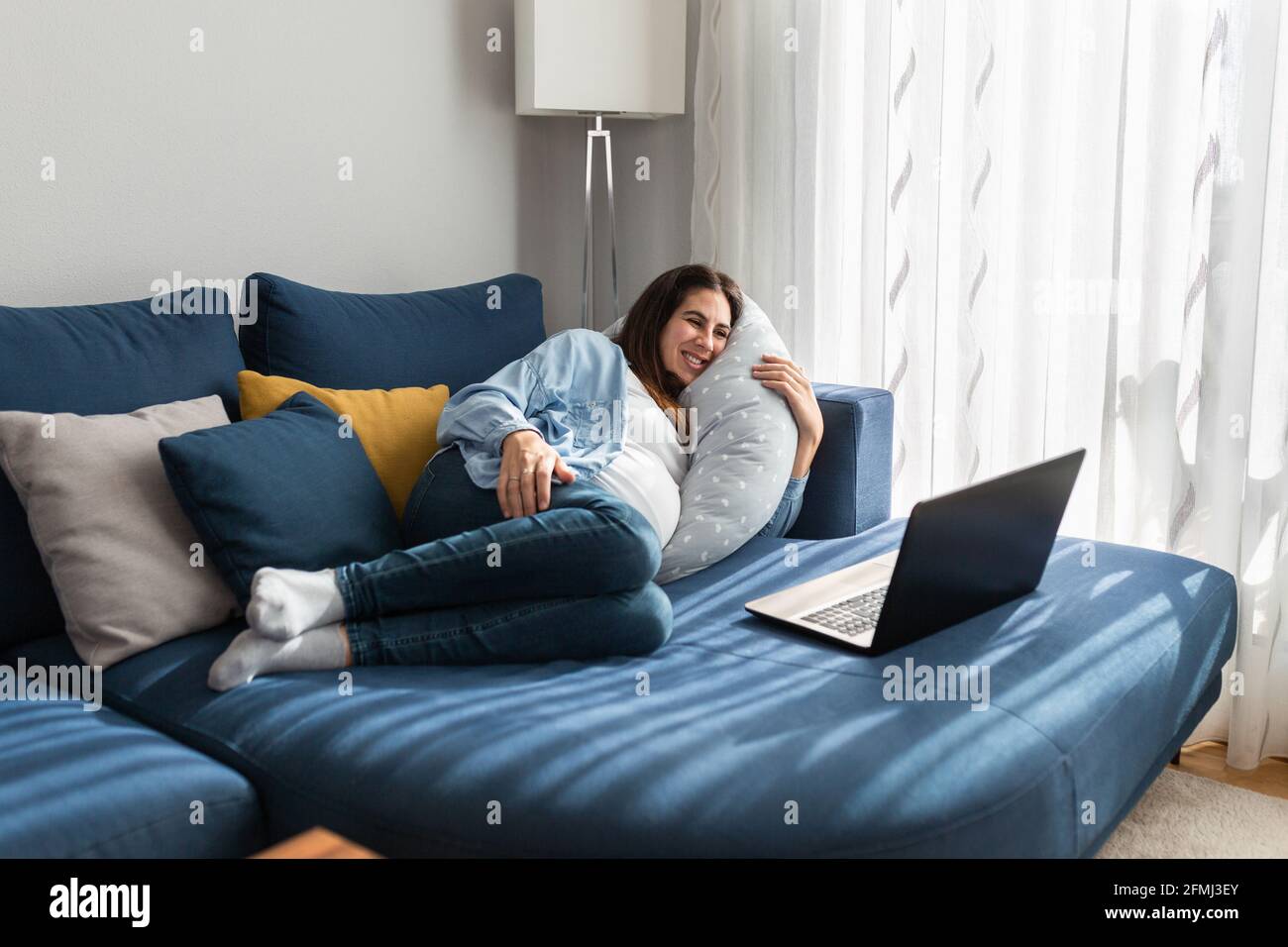 Delighted pregnant female lying on comfortable sofa and watching funny video on netbook while relaxing at home Stock Photo - Alamy Delighted pregnant female lying on comfortable sofa and watching funny video on netbook while relaxing at home Stock Photo - Alamy