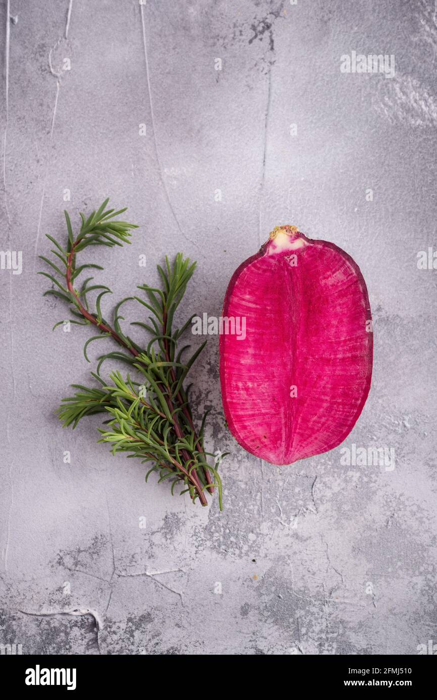 Top view of tender pink flower petal near aromatic rosemary sprigs on rugged surface with spots Stock Photo