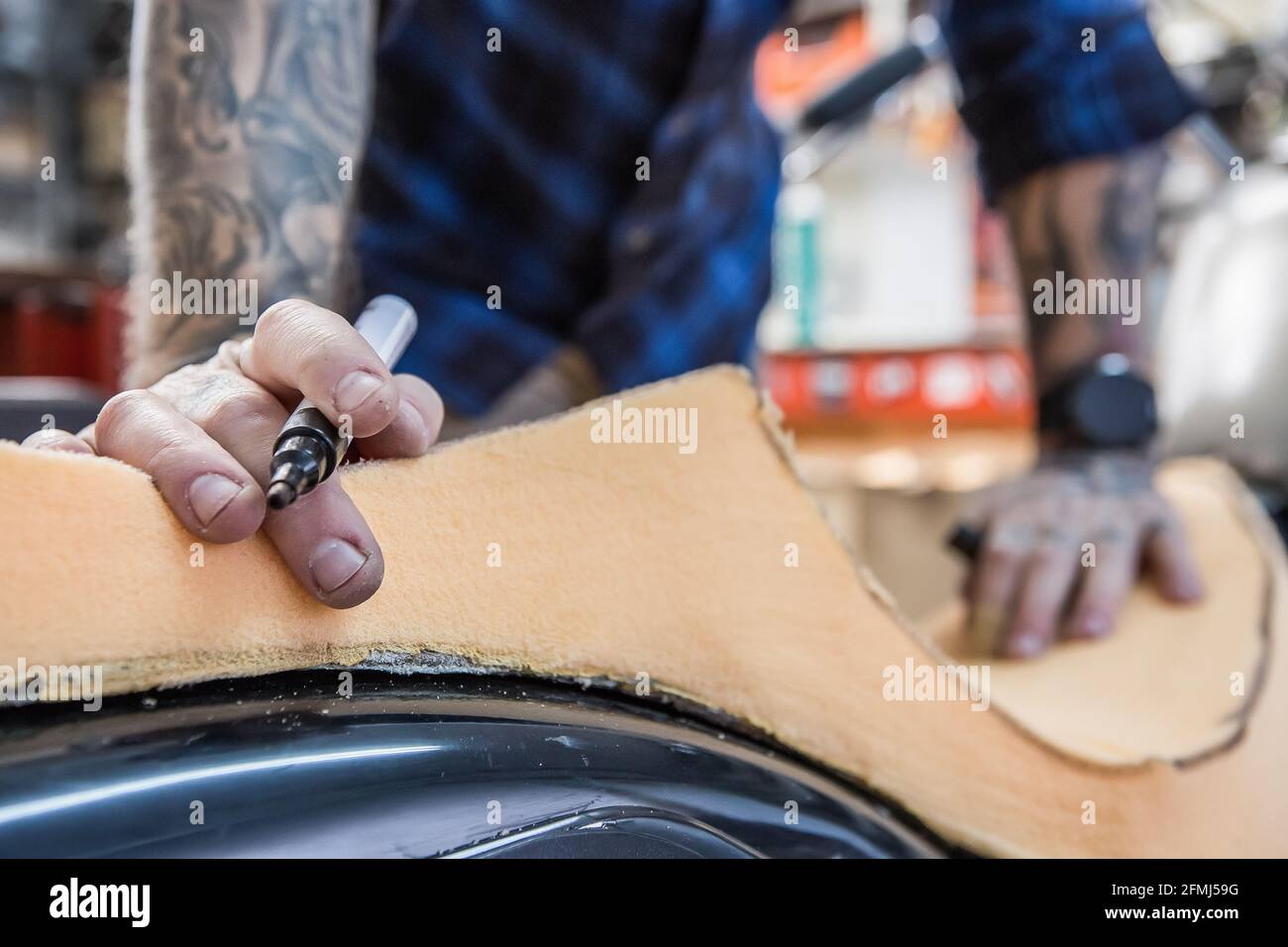 Crop craftsman using foam rubber for creating handmade motorcycle seat in workshop Stock Photo
