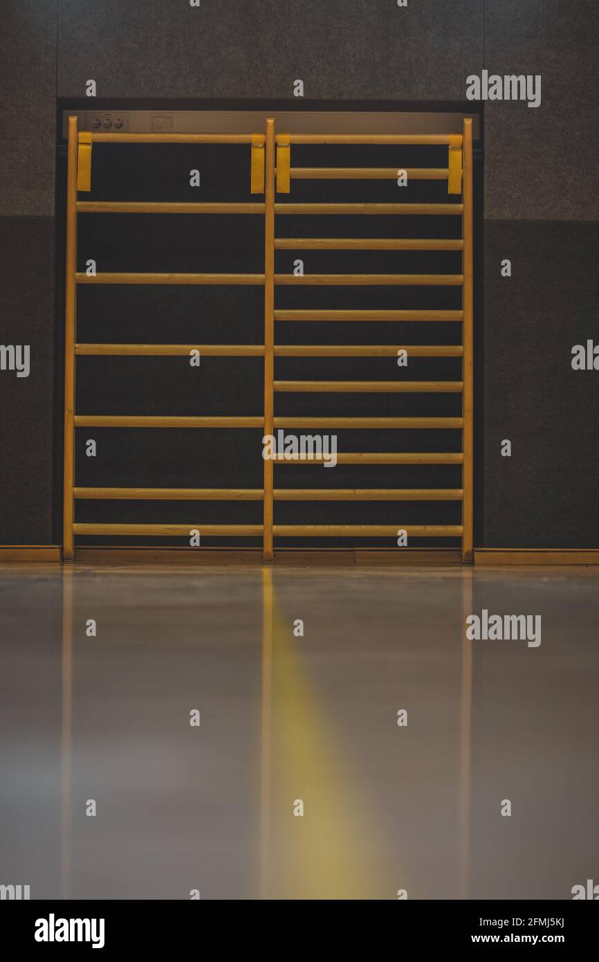 Frontal view of a wooden fitness ladder or bars, mounted on a wall in gym. Empty fitness bars. Stock Photo