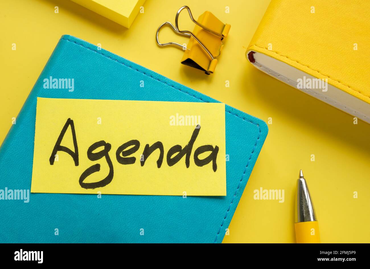 Piece of paper with word agenda and notepads. Stock Photo