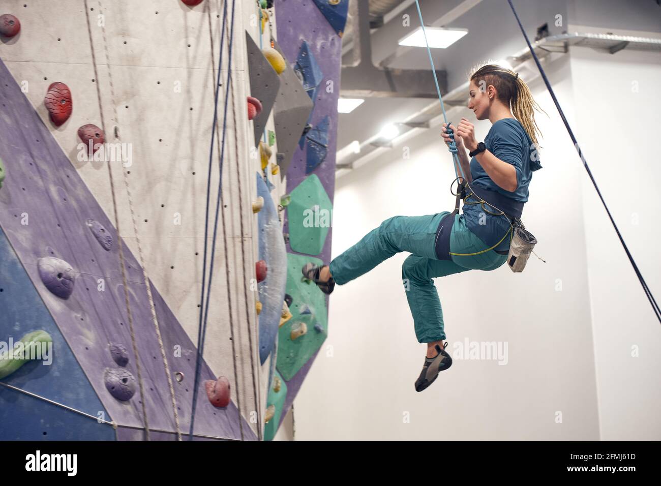 Side view of female alpinist hanging on safety equipment during