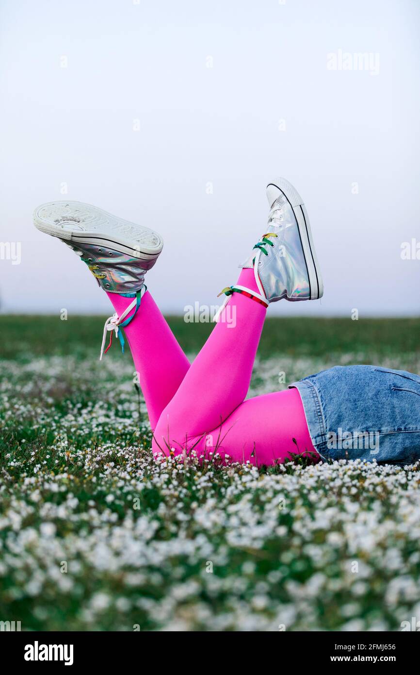 Crop faceless female wearing pink tights and denim shorts lying on lush  grassy meadow in summer countryside Stock Photo - Alamy