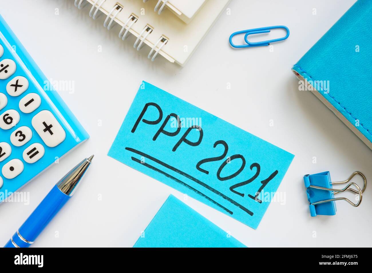 PPP loan 2021 handwritten words on a blue piece of paper. Stock Photo