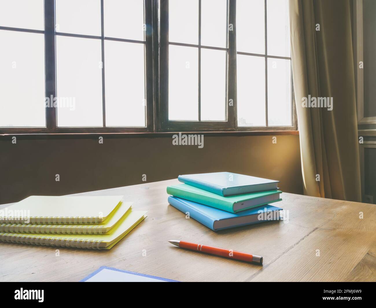 Office desk with papers, notepads and pen near window. Stock Photo