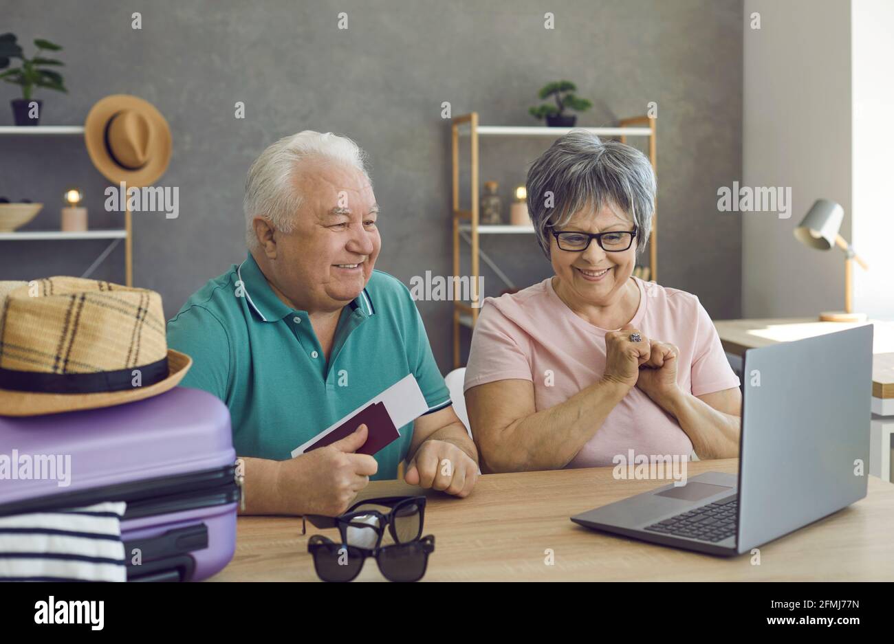 Happy senior couple planning holiday trip, using laptop and making hotel reservation online Stock Photo