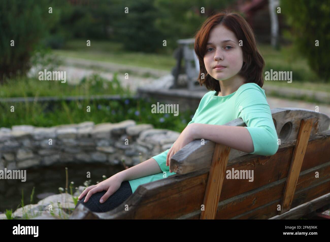 Girl sitting on a park bench near the pond Stock Photo - Alamy